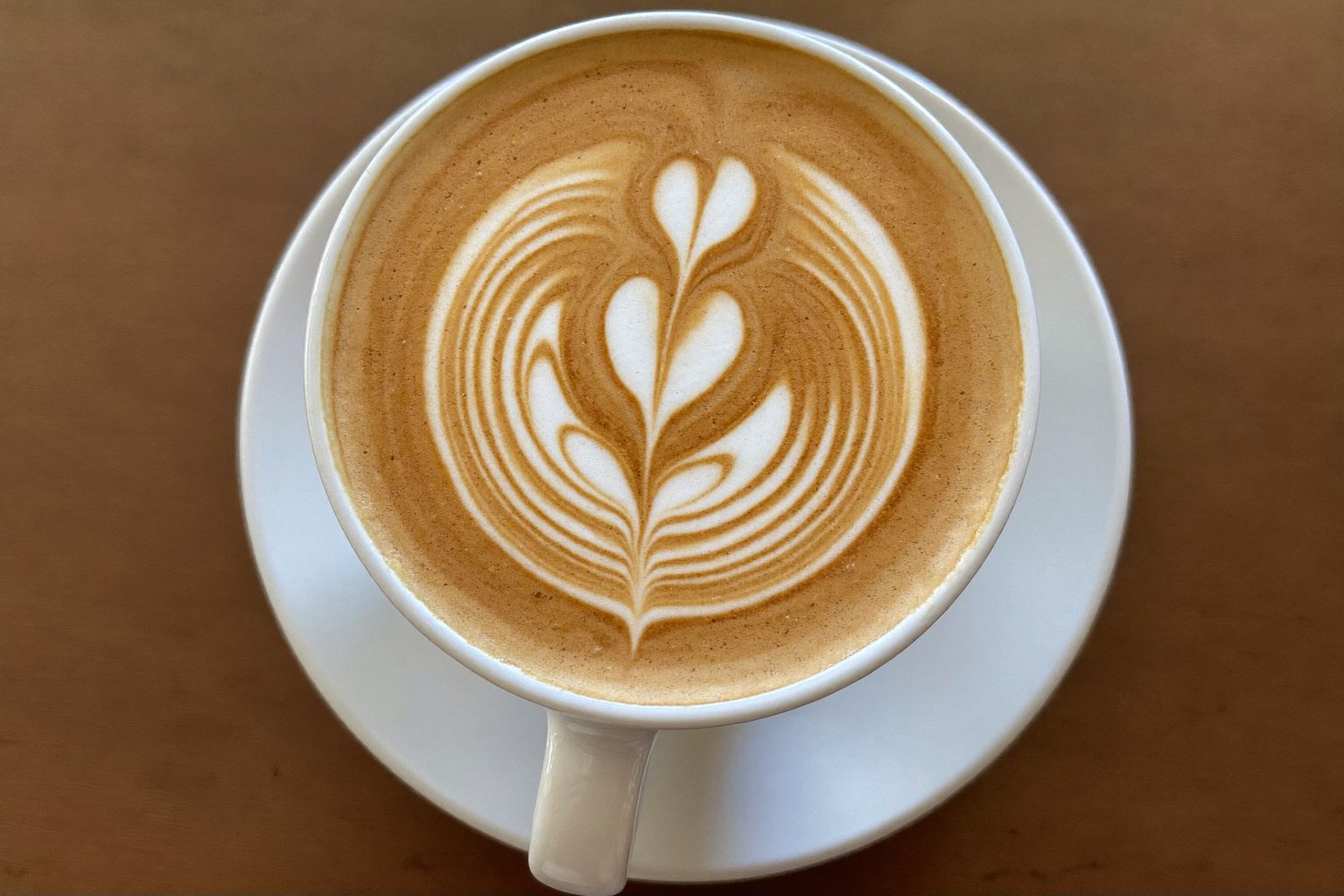 Barista giet latte art in een kopje achter de espressomachine