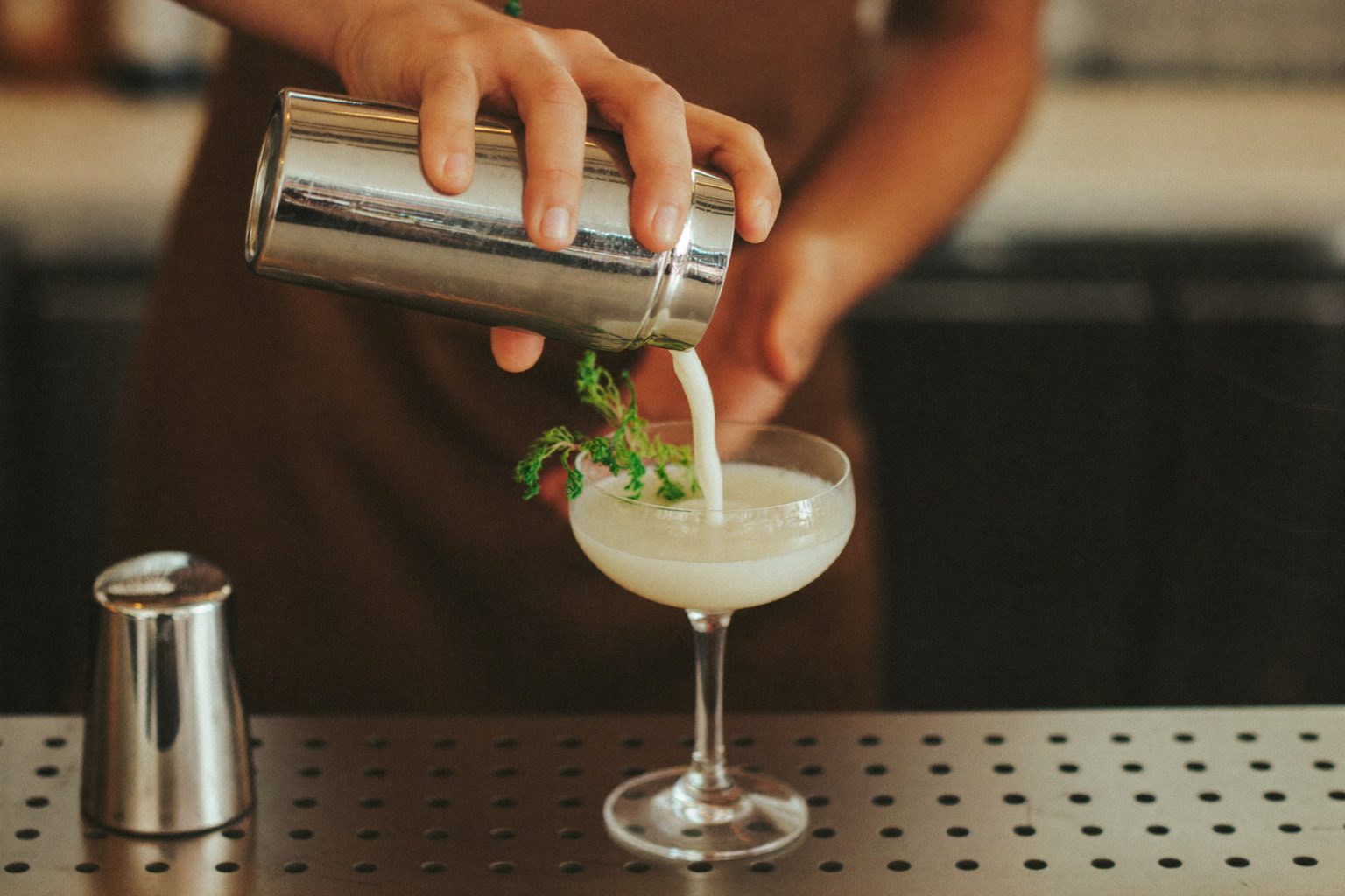 Bartender schudt een cocktailshaker achter een sfeervolle bar