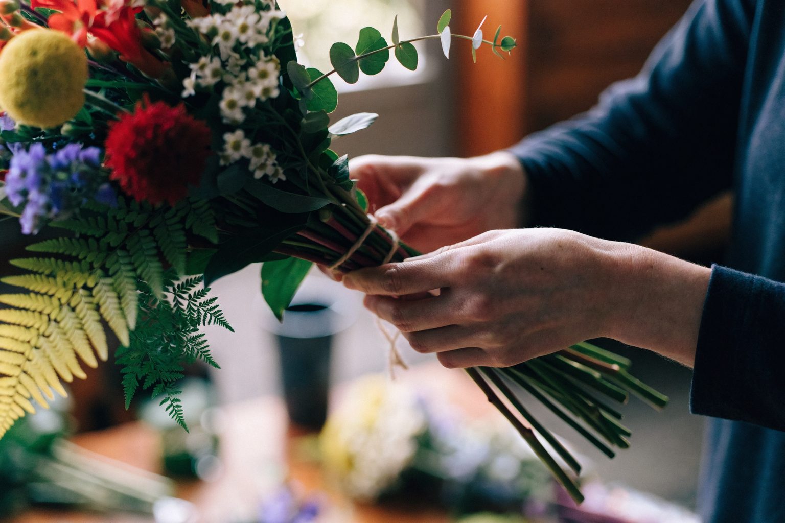 Bloemist bindt een kleurrijk boeket in een sfeervolle bloemenwinkel