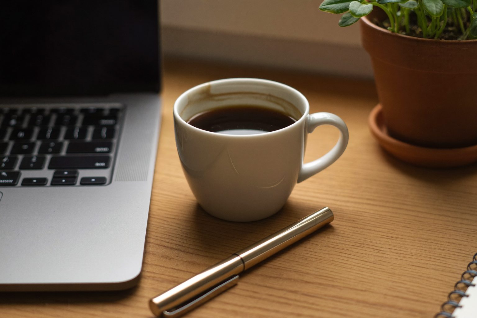 Copywriter werkt geconcentreerd aan een bureau met een laptop en een kop koffie