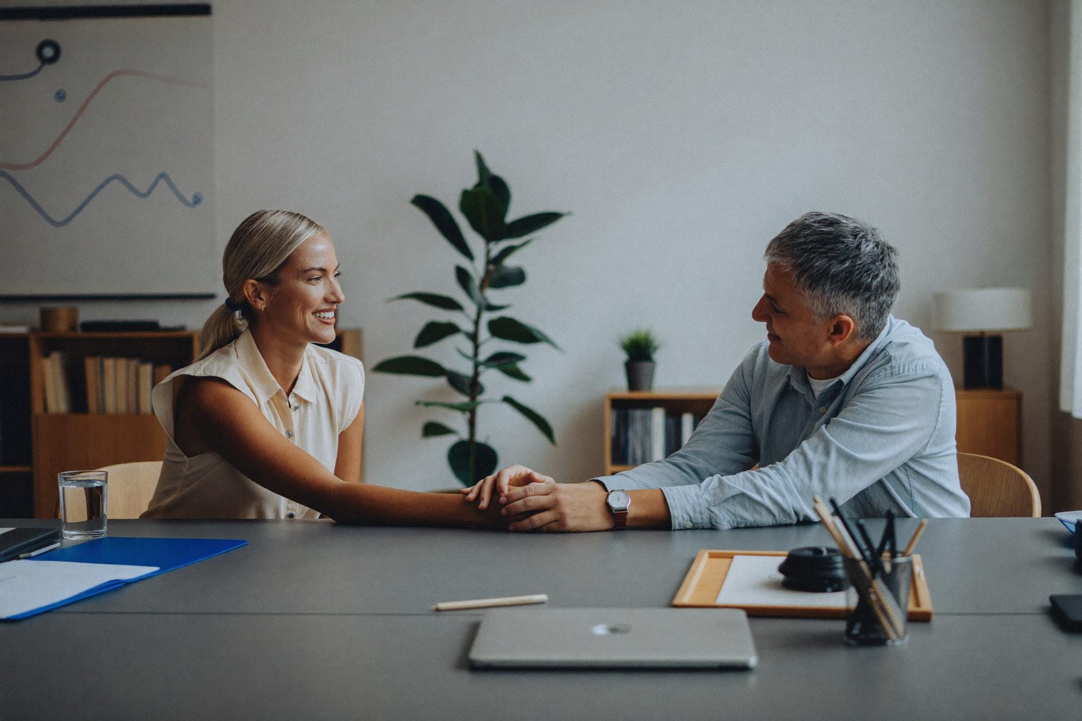 HR-medewerker verwelkomt een nieuwe collega met een handdruk in een licht kantoor