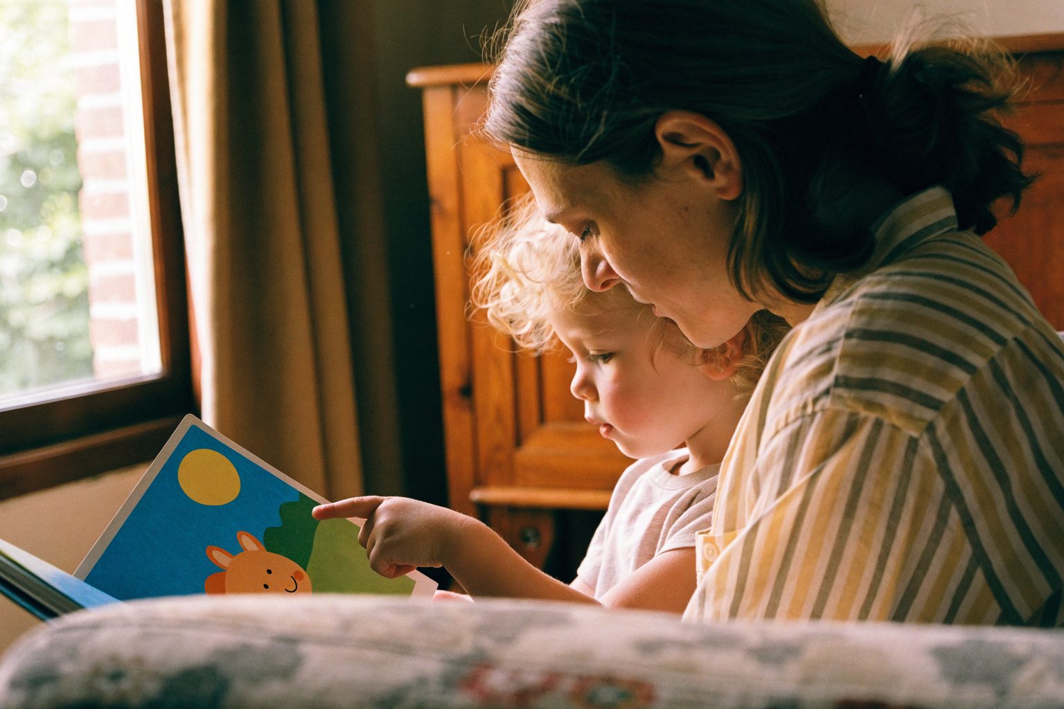 Volwassene leest een kleurrijk prentenboek voor aan een kind