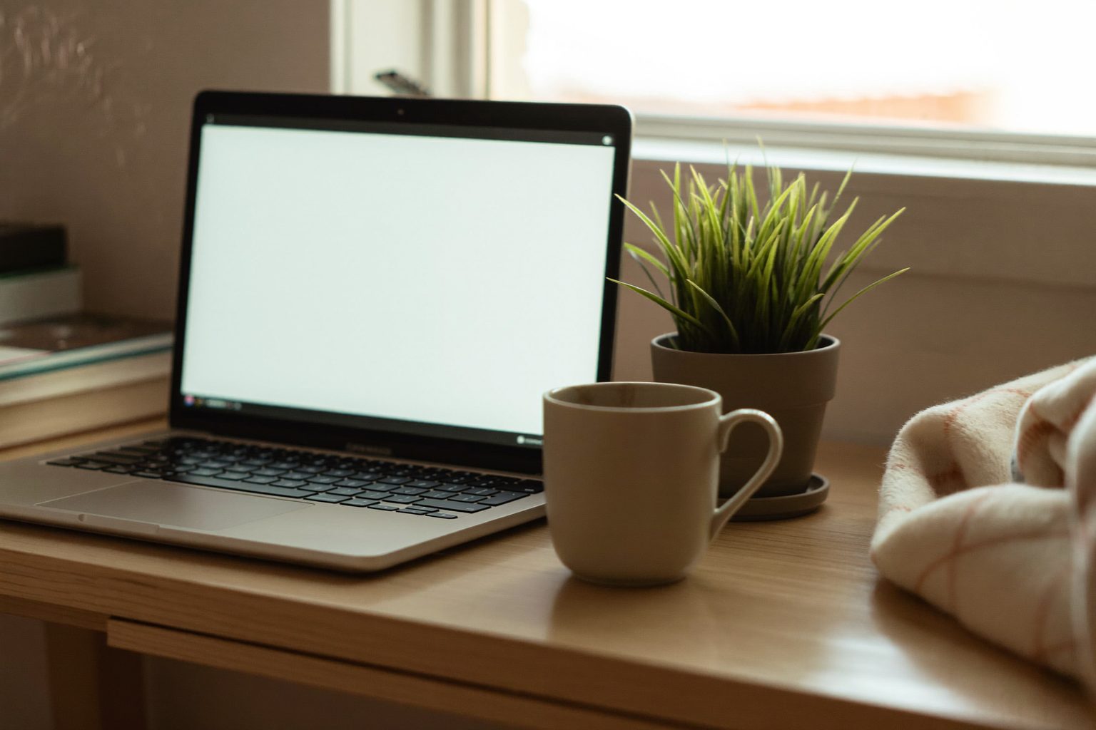 Iemand ontspannen thuis op de bank met een kop koffie en een dichtgeklapte laptop