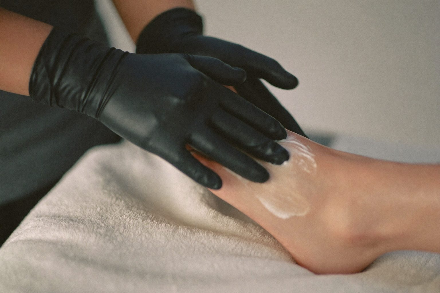Voetverzorger met handschoenen behandelt zorgvuldig de voet van een client in een schone praktijk