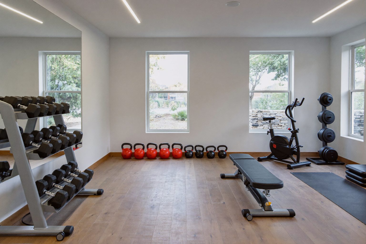 Een goed uitgeruste, lichte fitnessruimte met halters, kettlebells en toestellen